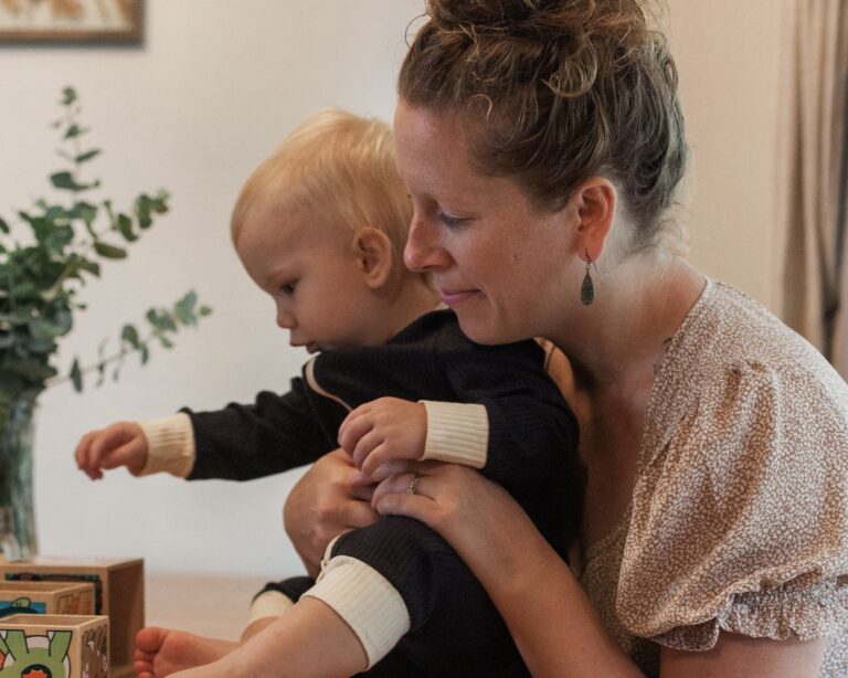 Smiling mom cuddling her baby — natural postpartum care essentials for body, mind, and spirit
