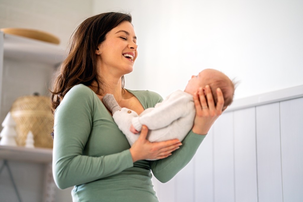 Smiling mom with healthy, glowing skin holding her baby — the payoff of choosing the best facial toner for your skin type