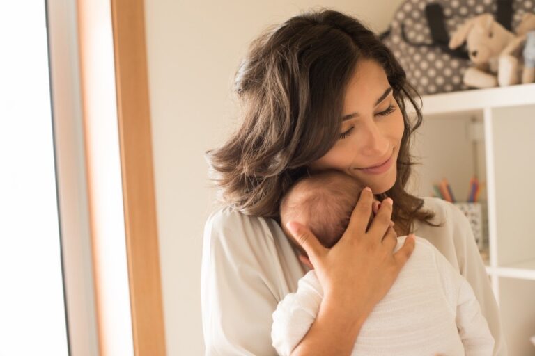 Mother with soft, natural skin tenderly holding her baby — a gentle postpartum skin care routine that is safe while nursing