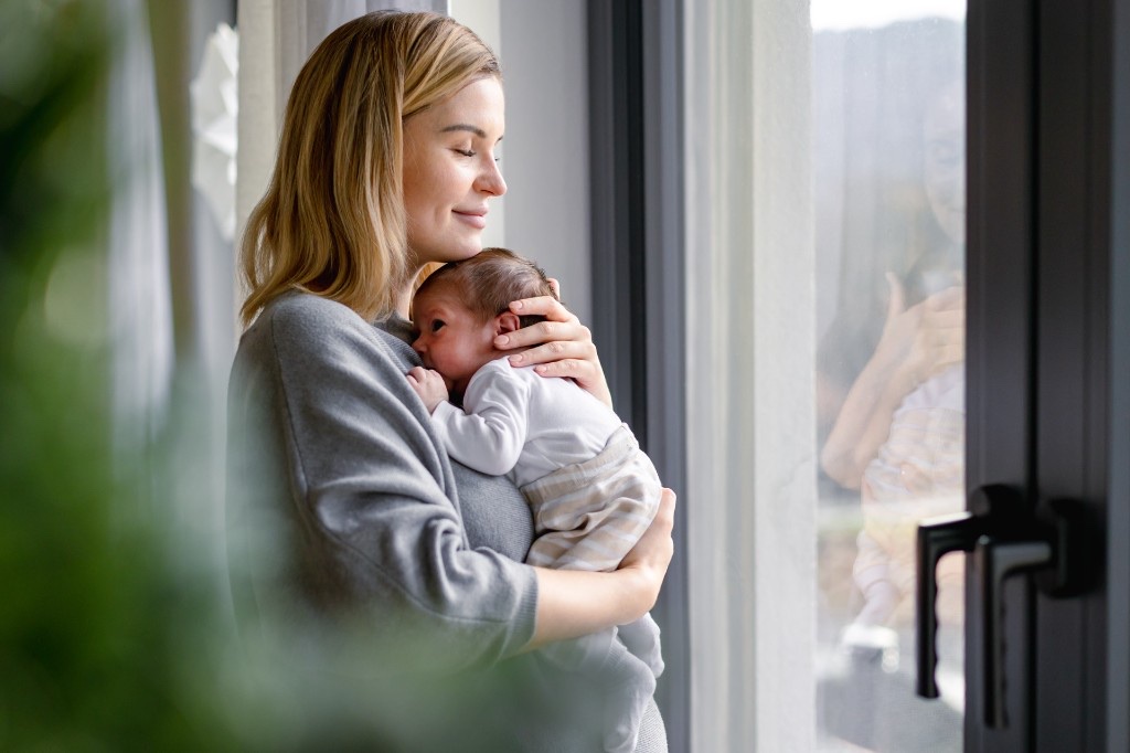 Calm, prepared postpartum mom snuggling her newborn — a complete postpartum checklist means recovery essentials are ready